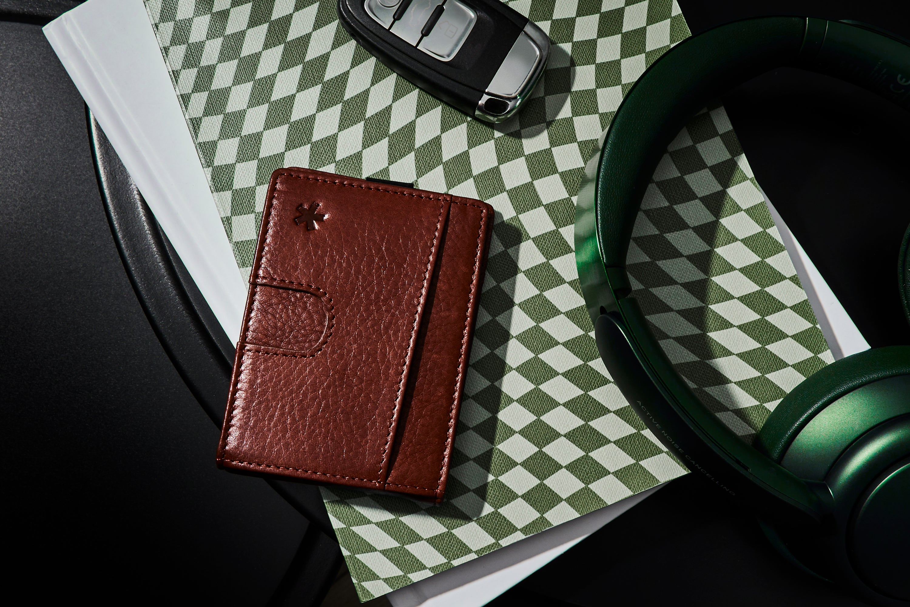 Wallet placed in lifestyle scene with headphones and keys.