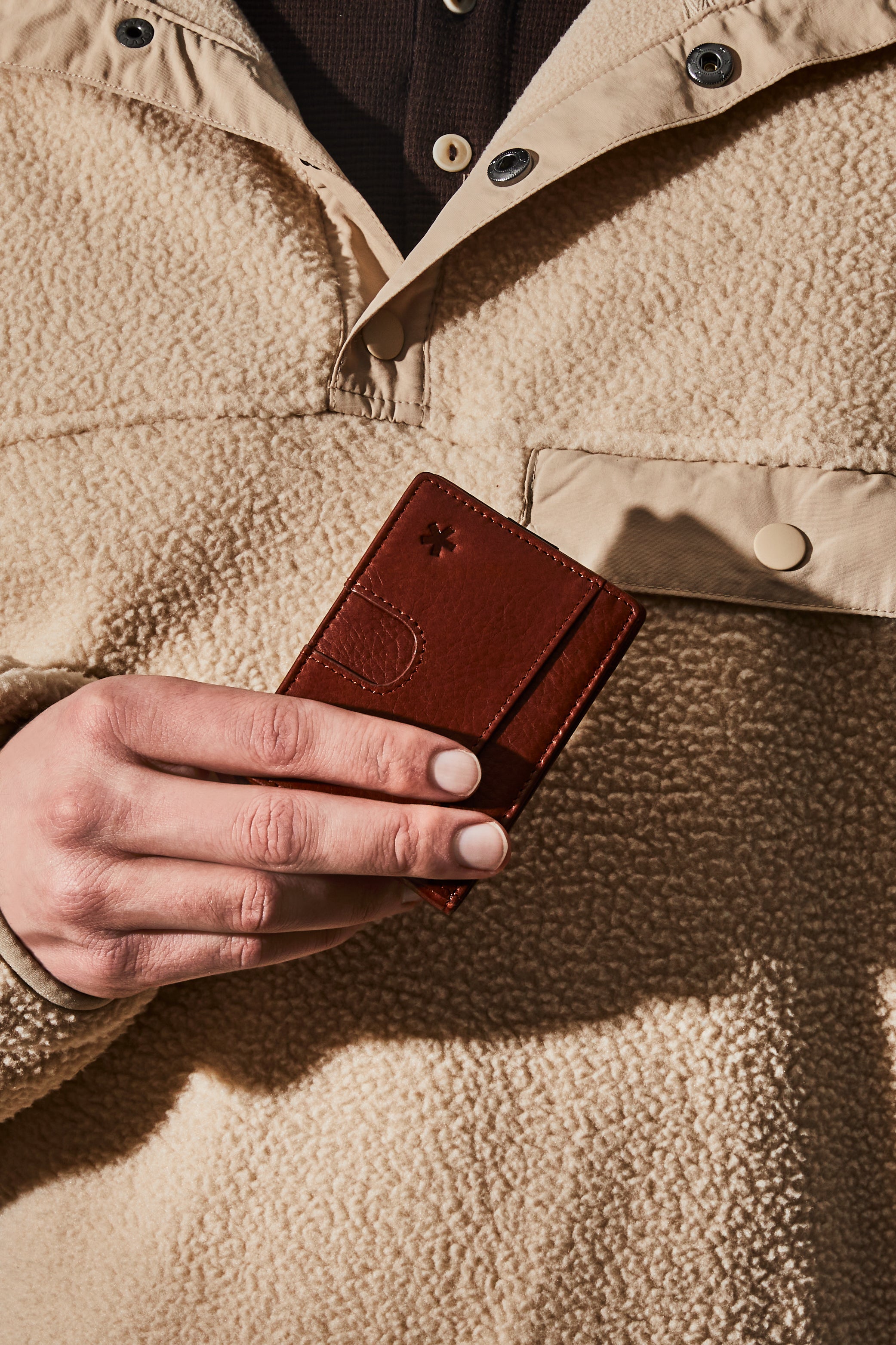 Man holding a brown leather wallet.